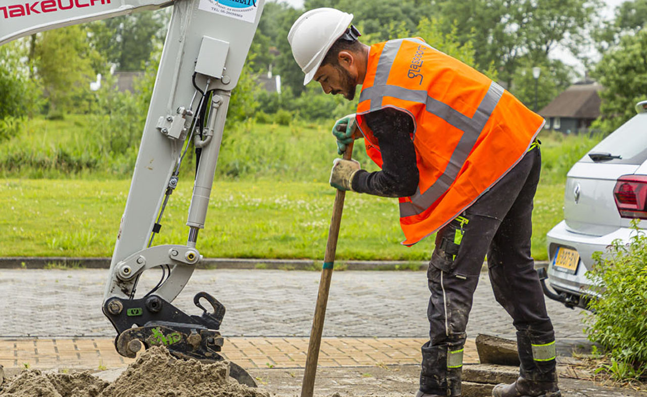 voor de glasvezelaanleg wordt er een geul gegraven met graafmachine